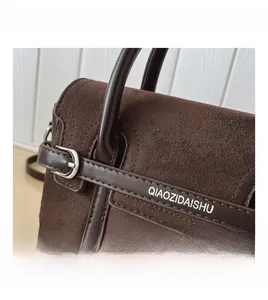 Détail en daim marron et cuir lisse avec boucle argentée et sangle logo de sac à main
