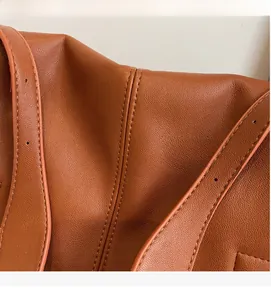 Detail of premium brown pebble leather texture and stitching on crossbody messenger bag