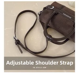 Détail de la bandoulière réglable et de l'anse en cuir d'un sac cabas en daim marron
