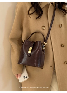 Retro dark brown bucket bag with gold clasp shown on a model in a wool coat