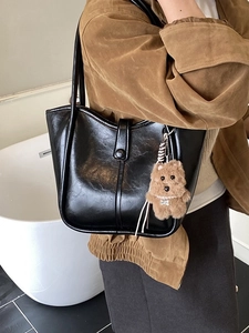 Fashionable black glossy leather bucket bag with cute plush bear charm for women