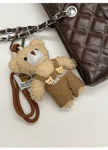 Detail of plush bear charm with knit trousers and lanyard on a quilted tote bag