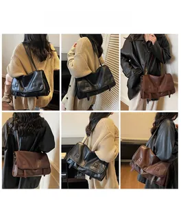 Model wearing a large vintage messenger bag in black and brown soft leather finish
