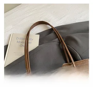 Detail eines kaffeebraunen Leder-Tote-Griffs mit Plüschhasen-Anhänger und feiner Naht
