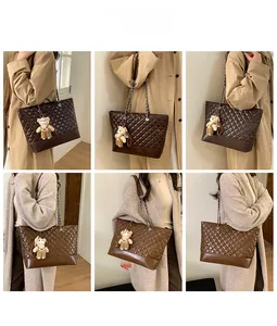 Detail of coffee brown quilted tote bag with chain strap and teddy bear charm