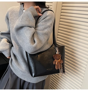 Detail of black faux leather tote bag with MIAOMIAO print and brown bear charm