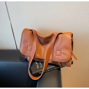 Close-up of a brown retro messenger bag in soft vegan leather with stylish strap detail