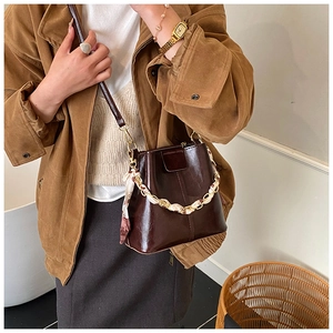 Detail of dark brown leather bucket bag with silk scarf wrapped chain and slim strap