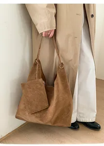 Close-up of brown suede tote bag featuring a detachable small matching zipper pouch