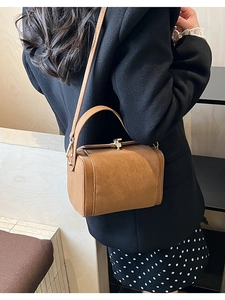 Detailed side view of vintage brown satchel bag with matte texture on a female model