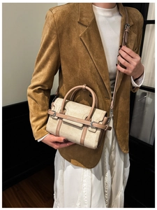 Détail d'un sac à main en daim beige avec bordure en cuir marron porté par un modèle