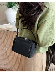 Detail of a vintage black doctor bag featuring a matte leather finish and gold metal clasp
