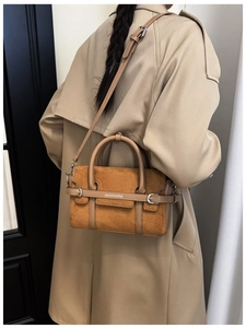 Détail du sac à main en daim caramel porté sur un trench-coat élégant de couleur beige