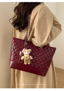 Deep red quilted tote bag featuring metal chain straps and a plush bear charm detail
