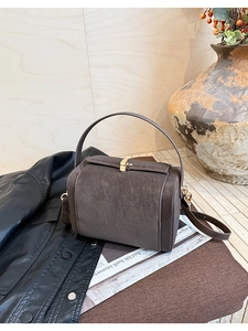 Detail shot of vintage dark brown leather box bag with a golden metal rotary clasp