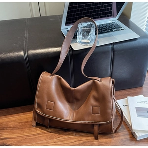 Detail of vintage brown leather satchel with contrast stitching on wooden floor