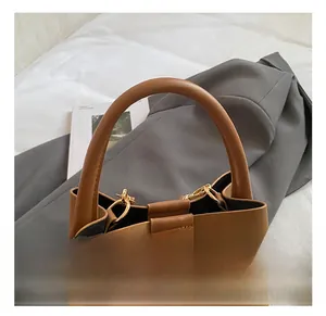 Dettaglio di una borsa a secchiello in pelle marrone con manico tondo e logo GOCDCH