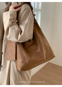Detail of a large brown suede tote bag with a matching small pouch worn by a model