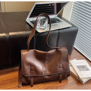 Deep brown retro leather messenger bag displayed with laptop and books on wooden floor