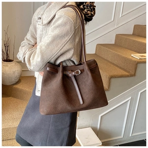 Detailed view of dark brown woven texture tote bag with leather strap and metal buckle