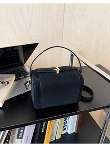 Detail of a vintage black suede crossbody bag with gold metallic lock and top handle