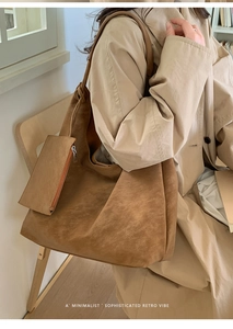 Detail of a large retro brown suede tote bag worn by a model in a minimalist indoor setting