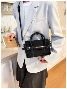 Détail du sac en cuir noir avec logo lettré et boucle de ceinture sur le rabat