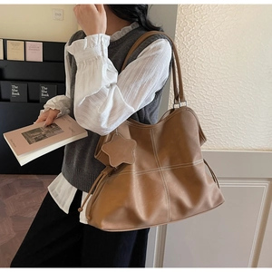 Brown faux leather tote bag with white cross-stitching and star charm detail
