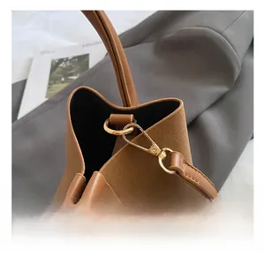 Dettaglio macro del gancio in metallo oro chiaro su una borsa a secchiello in pelle marrone