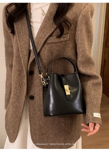 Close-up of a black leather bucket bag featuring a refined gold-tone metal twist lock