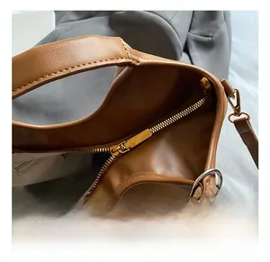 Detail of premium golden metal zipper and smooth brown leather on large bucket bag