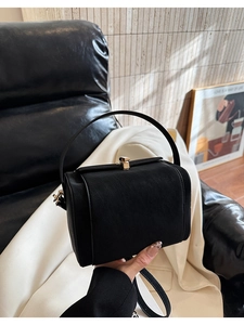 Close-up of black suede and smooth leather bag with elegant gold metal clasp detail