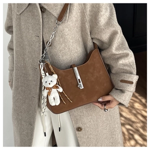 Detailed close-up of brown vintage leather underarm bag with silver buckle and plush bear charm