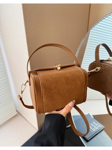 Detail of camel brown vintage handbag showing gold metal buckle and smooth faux leather texture