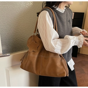 Close-up of brown vintage tote bag with white contrast stitching and star charm