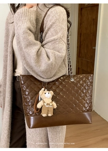 Close-up of vintage brown quilted tote bag with silver chain strap and cute bear charm