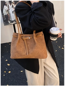 Detail of brown woven leather tote bag with long shoulder strap and adjustable buckle
