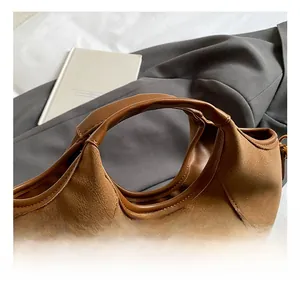 Detail of reinforced stitched handles on a vintage brown leather bucket bag with texture