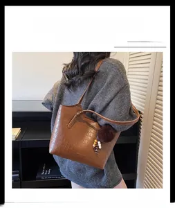 Detail of retro brown bucket bag with crocodile pattern and decorative plush charm