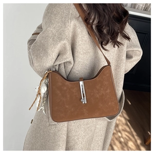 Brown suede shoulder bag with silver piston clasp shown on a beige wool coat