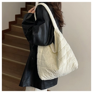 Détail du grand sac cabas matelassé blanc à motif damier porté par un mannequin en cuir