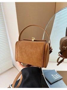 Detail of a brown vintage satchel with litchi texture and golden metal clasp lock