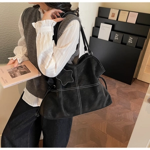 Detail of large black tote bag with white contrast stitching and star patch detail