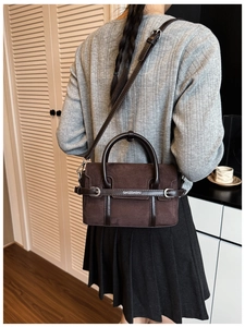 Sac bandoulière en daim marron foncé porté par un modèle pour référence de taille et style