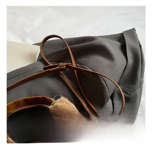 Detail of adjustable leather shoulder strap and cute plush bear charm on a brown bucket bag