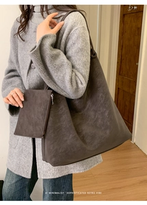 Minimalist dark charcoal leather tote bag with small pouch shown in home setting