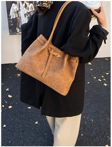 Detail of a brown woven tote bag showing its textured faux leather and long shoulder straps