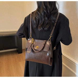 Detail of vintage brown leather backpack with gold rotary lock on black coat