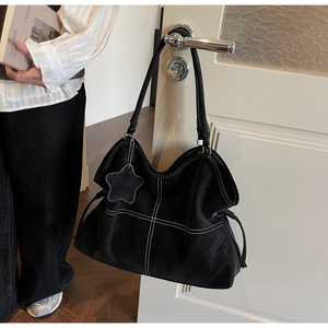 Detail of black tote bag featuring white contrast stitching and a star pendant