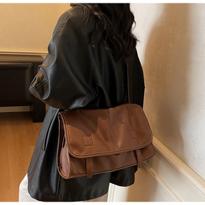 Close-up of vintage brown messenger bag with detailed leather texture and buckled flap